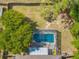 Aerial close-up of a backyard pool enclosed by a screened patio, surrounded by lush trees at 3485 Dothan Ave, Spring Hill, FL 34609