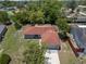 Aerial view of the home showcasing its red roof, fenced yard, and proximity to lush greenery at 3529 Orion Rd, Spring Hill, FL 34606