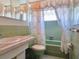 Retro bathroom with light green tiling, seashell curtain, and matching green toilet and bathtub at 3605 100Th N Ter, Pinellas Park, FL 33782