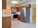 Efficient kitchen with wood cabinets, white appliances, and tile flooring with adjacent living area at 3605 100Th N Ter, Pinellas Park, FL 33782