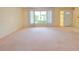 Neutral living area features plush carpeting, large window, and access to the home's front entrance at 3605 100Th N Ter, Pinellas Park, FL 33782