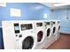 Well-lit community laundry room featuring modern commercial washers against a blue wall at 4702 Michael Ct # 139, Tampa, FL 33614