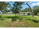 Backyard featuring an expansive green lawn with trees and a glimpse of the home's back exterior at 5391 54Th N St, St Petersburg, FL 33709