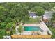 Aerial view of a backyard oasis with a large pool, a spa, palm trees, white gravel, a wood fence and lush greenery at 6 N Orion Ave, Clearwater, FL 33765