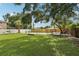 Fenced backyard with lush grass, mature trees, and a view of the property's exterior at 6 N Orion Ave, Clearwater, FL 33765