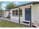 Charming home featuring a blue entry door, white exterior, dark trim, and a well-manicured lawn at 6 N Orion Ave, Clearwater, FL 33765