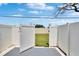 View of the white fenced-in backyard, with a charming gate that leads to a lush, green lawn at 6601 121St Ave # I, Largo, FL 33773