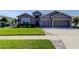 Charming single-story home featuring a well-manicured lawn, a two-car garage and stone facade accents at 6648 Castle Green Pl, Zephyrhills, FL 33541