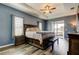 This main bedroom features beautiful blue walls, a ceiling fan, and an ensuite bathroom at 6648 Castle Green Pl, Zephyrhills, FL 33541