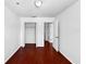 Bright bedroom featuring hardwood floors, white walls, and closet and hallway access at 7711 Nottinghill Sky Dr, Apollo Beach, FL 33572