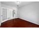 Inviting bedroom showcasing rich, dark wood floors, with French doors and a closet, offering a warm, spacious feel at 7711 Nottinghill Sky Dr, Apollo Beach, FL 33572