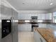 Kitchen features stainless steel refrigerator, granite countertops, and access to the adjacent living area at 7711 Nottinghill Sky Dr, Apollo Beach, FL 33572