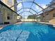 Screened-in pool with waterfall and surrounding brickwork, perfect for outdoor relaxation and entertaining at 7711 Nottinghill Sky Dr, Apollo Beach, FL 33572