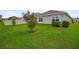 This backyard features an newly planted tree, green grass, and a white fence at 7774 Sail Clover Ln, Zephyrhills, FL 33540