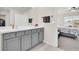The bathroom features dual sinks, grey cabinets, a large mirror, and tile flooring with a glimpse into the bedroom at 7774 Sail Clover Ln, Zephyrhills, FL 33540