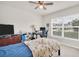 Bright bedroom with a large window, a ceiling fan, and a dedicated desk area at 7774 Sail Clover Ln, Zephyrhills, FL 33540