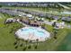 Aerial view of a community pool with palm trees, a covered seating area, and green lawns at 7774 Sail Clover Ln, Zephyrhills, FL 33540