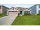 This single-story home features neutral paint, blue shutters, and landscaping, and a two-car garage at 7774 Sail Clover Ln, Zephyrhills, FL 33540