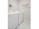 This cozy laundry room includes a white washer and dryer and decorative decals at 7774 Sail Clover Ln, Zephyrhills, FL 33540
