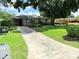 Exterior view of a cozy home with a long driveway and well-maintained lawn at 7908 Croton Ave, Tampa, FL 33619