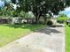 View of the house with a long driveway, front lawn, and mature trees providing shade at 7908 Croton Ave, Tampa, FL 33619