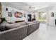 Open living room with gray sofa, tiled floors, and sliding glass doors leading to the patio at 8050 Diablo Ct, Trinity, FL 34655