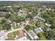 An aerial view shows a neighborhood with mature trees and varying home styles on a sunny day at 8701 N Packwood Ave, Tampa, FL 33604