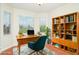 Well-lit home office with a desk, comfortable chair, bookshelf, and large windows offering green views at 9067 39Th Street E Cir, Parrish, FL 34219