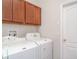 Laundry room featuring a white washer and dryer with wooden cabinets above at 9067 39Th Street E Cir, Parrish, FL 34219