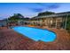 A sparkling blue swimming pool surrounded by brick, with an outdoor seating area, and a privacy fence at 11236 116Th St, Largo, FL 33778