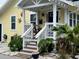 Charming yellow home featuring a cozy front porch, lush plants, and white gravel landscaping at 1137 Highland S St, St Petersburg, FL 33701