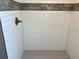A tiled shower stall featuring white subway tiles and decorative gray wood-look accent stripe at 1137 Highland S St, St Petersburg, FL 33701