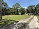 View of expansive lawn and long gravel driveway beneath a blue sky surrounded by lush trees at 12319 Memorial Hwy, Tampa, FL 33635