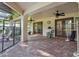 Spacious covered patio area featuring brick pavers, ceiling fans, and access to the pool area through a safety fence at 13747 Forest Ridge Ct, Hudson, FL 34667