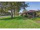 Well-manicured front yard with lush green grass, mature trees, and a charming screened-in porch, showcasing curb appeal at 13747 Forest Ridge Ct, Hudson, FL 34667