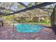 Beautiful backyard pool featuring brick pavers, a fully screened enclosure, and serene views of the surrounding landscape at 13747 Forest Ridge Ct, Hudson, FL 34667