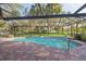 The backyard pool area is fully screened, complete with brick pavers surrounding the pool, and view of mature trees at 13747 Forest Ridge Ct, Hudson, FL 34667