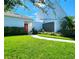 Contemporary home featuring a well manicured lawn and an attached two-car carport with a red front door at 14113 Cypress Cir, Tampa, FL 33618