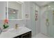 Bathroom featuring black and gold vanity, decorative mirror, and glass door shower with marble-look tiles at 1608 Carlos Ave, Clearwater, FL 33755