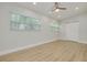 An airy bedroom with wood-look flooring, ceiling fan, two windows, and a closet with double doors at 1608 Carlos Ave, Clearwater, FL 33755