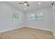 A bright bedroom featuring wood-look flooring, two windows, a ceiling fan, and light blue walls at 1608 Carlos Ave, Clearwater, FL 33755