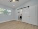 Bedroom with barn door access to the bathroom, light blue walls, and wood-look flooring at 1608 Carlos Ave, Clearwater, FL 33755