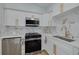A well-lit kitchen featuring white cabinets, marble backsplash, stainless steel appliances, and gold hardware at 1608 Carlos Ave, Clearwater, FL 33755