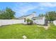 Exterior view of a well-maintained backyard with green grass, a white fence, and lush landscaping at 1763 Pebble Hill Ct, Palm Harbor, FL 34683