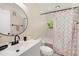 This bathroom includes a rounded mirror, and a shower/tub combination with white tile and patterned shower curtain at 1763 Pebble Hill Ct, Palm Harbor, FL 34683