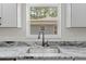 Close up of the kitchen sink featuring modern fixtures, grey cabinets and granite countertops at 19267 Wildwood Dr, Brooksville, FL 34601