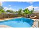Serene backyard featuring an in-ground pool, lounge chairs, lush greenery, and a privacy fence at 218 N Bay Hills Blvd, Safety Harbor, FL 34695