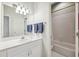 Bright bathroom featuring a tub shower, tile floors, and a large mirror with vanity lighting at 2404 W Jetton Ave, Tampa, FL 33629