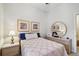 Inviting bedroom with a round mirror, soft lighting, and a comfortable bed adorned with decorative pillows at 2404 W Jetton Ave, Tampa, FL 33629