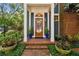 Charming entryway featuring a wooden door, lush greenery, brick steps, and a well-maintained exterior at 2404 W Jetton Ave, Tampa, FL 33629